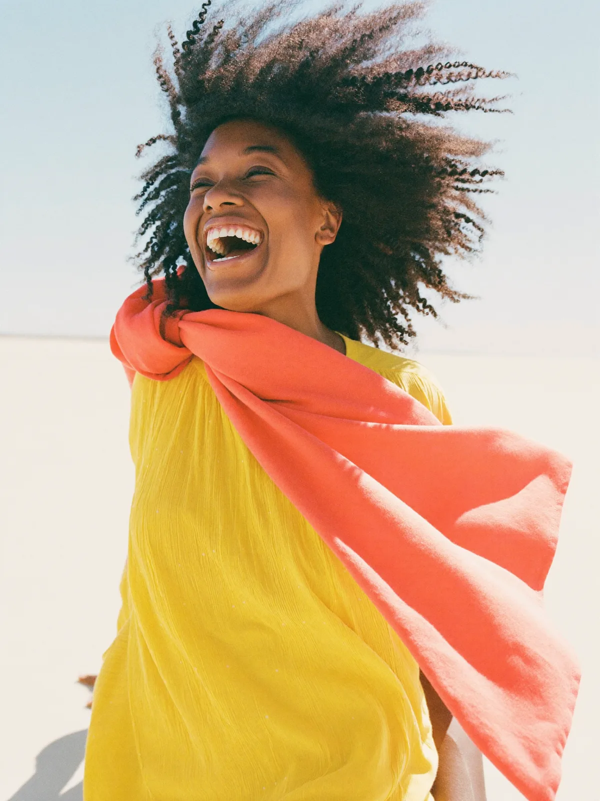 A woman laughing in bright sunshine, full of energy